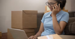 A lady tralking on the pone while working on a laptop